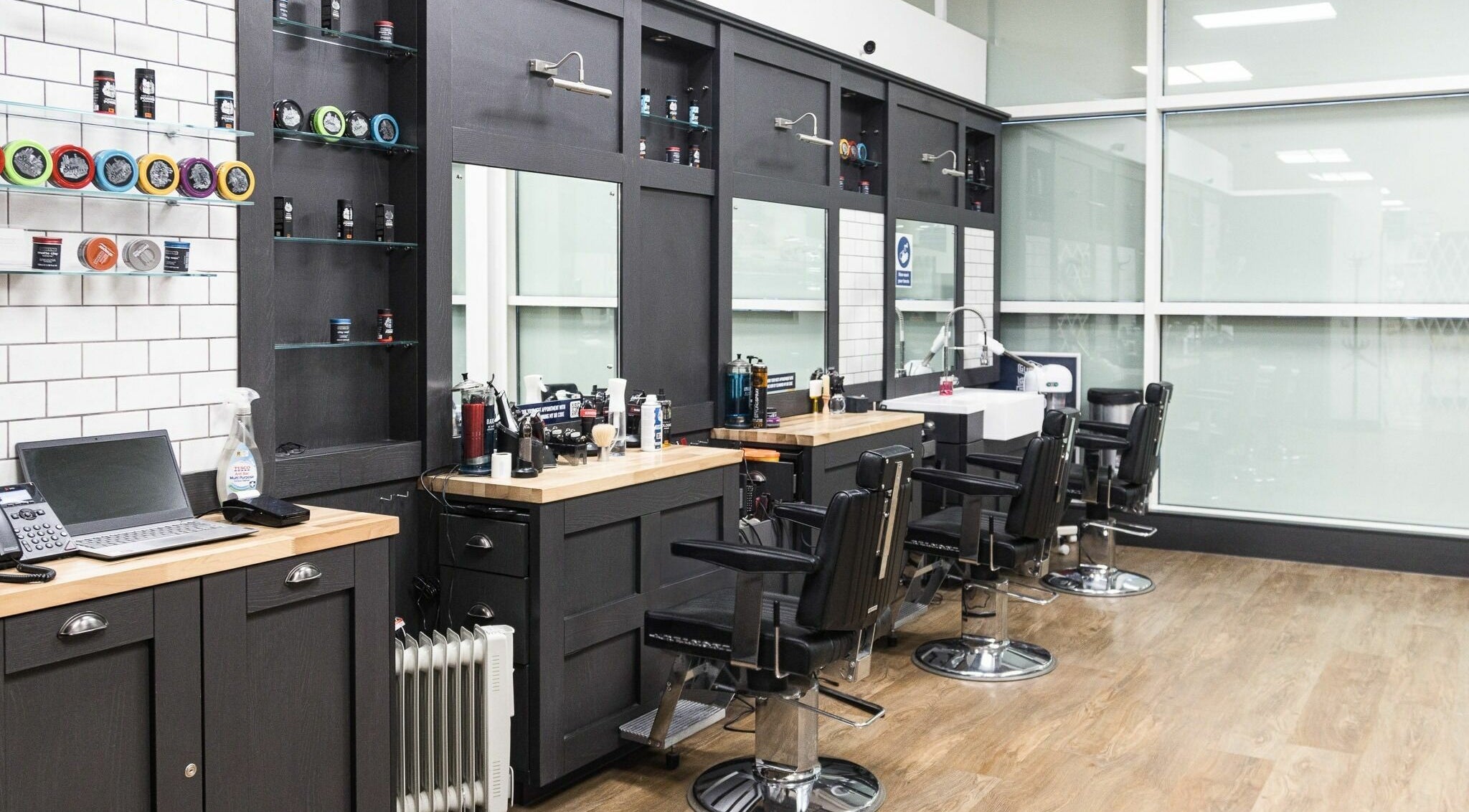 Modern barber station at Gould Barbers Southport, Southport, England, GB. Sleek chairs and styling products visible.