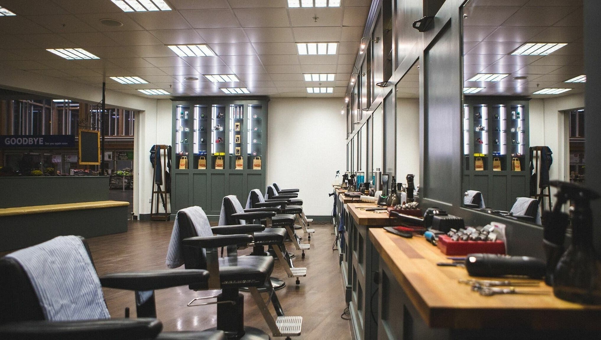 Interior of Gould Barbers Chesterfield, England, GB. Stylish barber chairs with grooming tools on wooden counters.