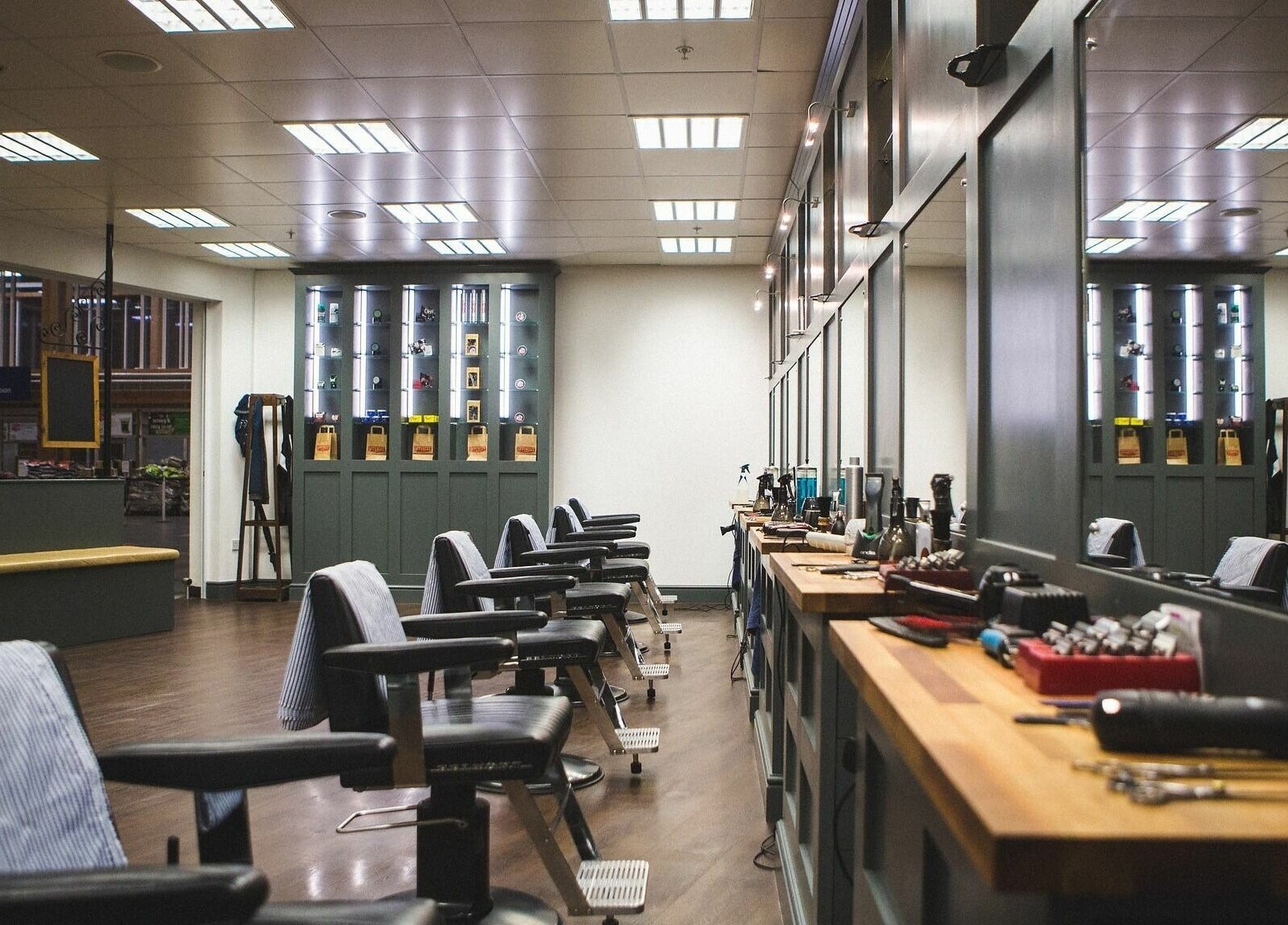 Interior of Gould Barbers Chesterfield, England, GB. Stylish barber chairs with grooming tools on wooden counters.