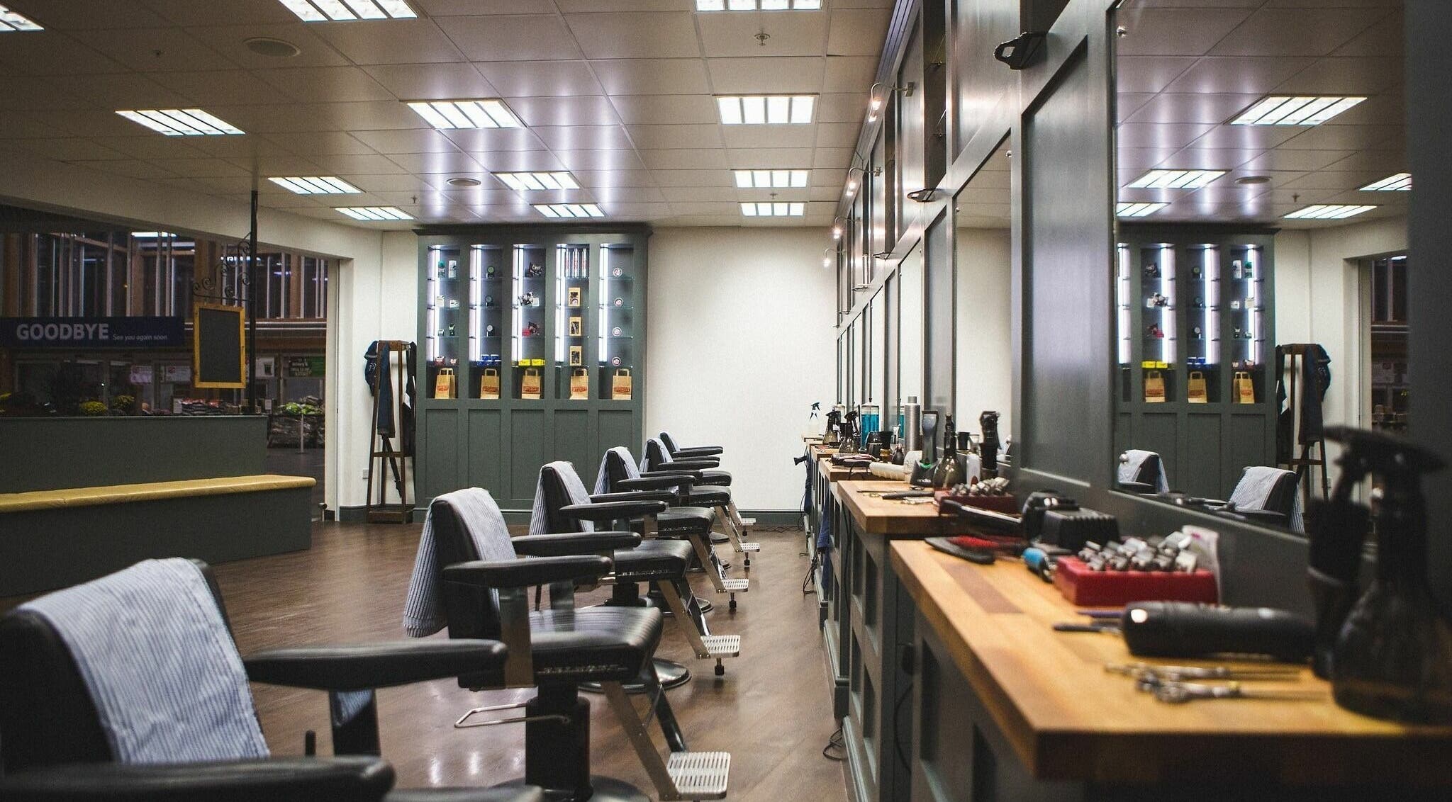 Interior of Gould Barbers Chesterfield, England, GB. Stylish barber chairs with grooming tools on wooden counters.