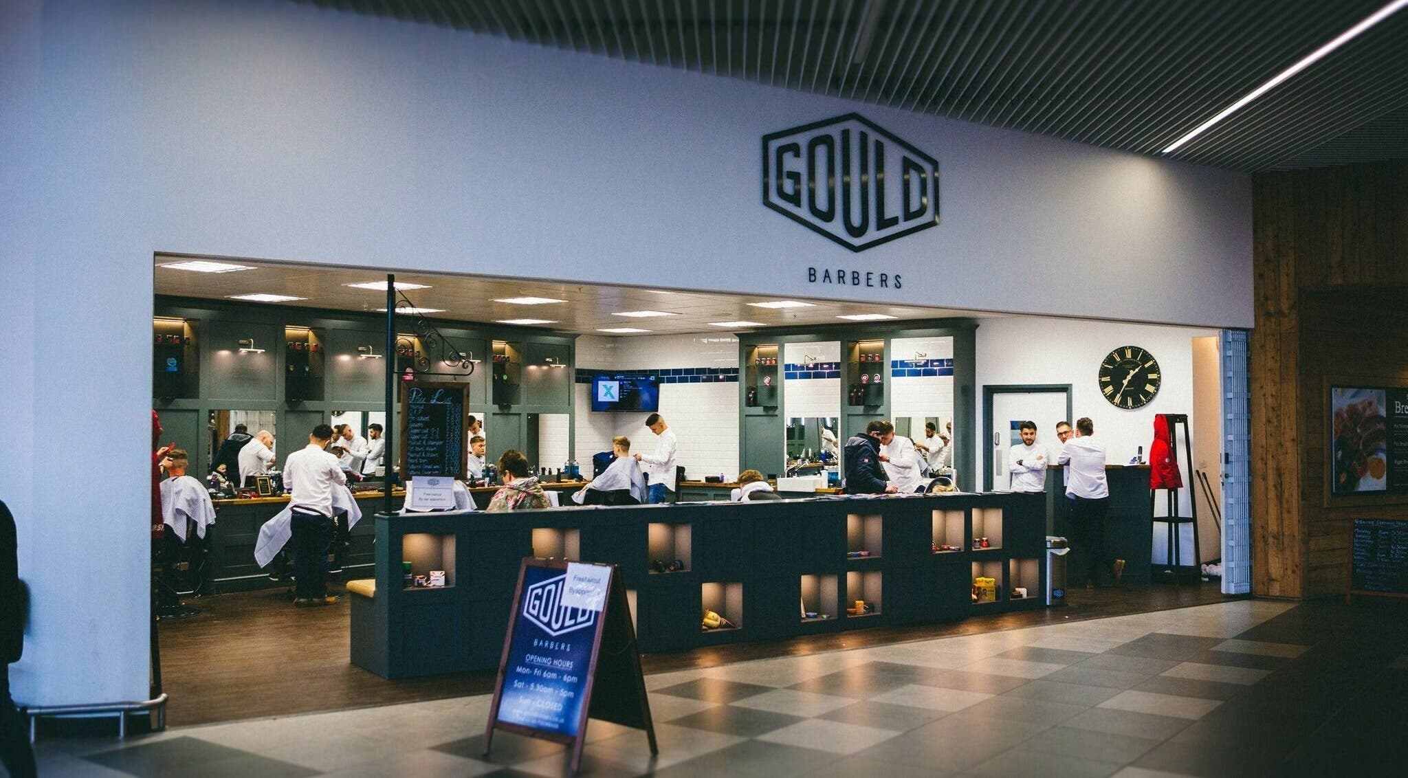 Interior of Gould Barbers Chesterfield, England, GB. Modern setup with barbers at work in a welcoming atmosphere.