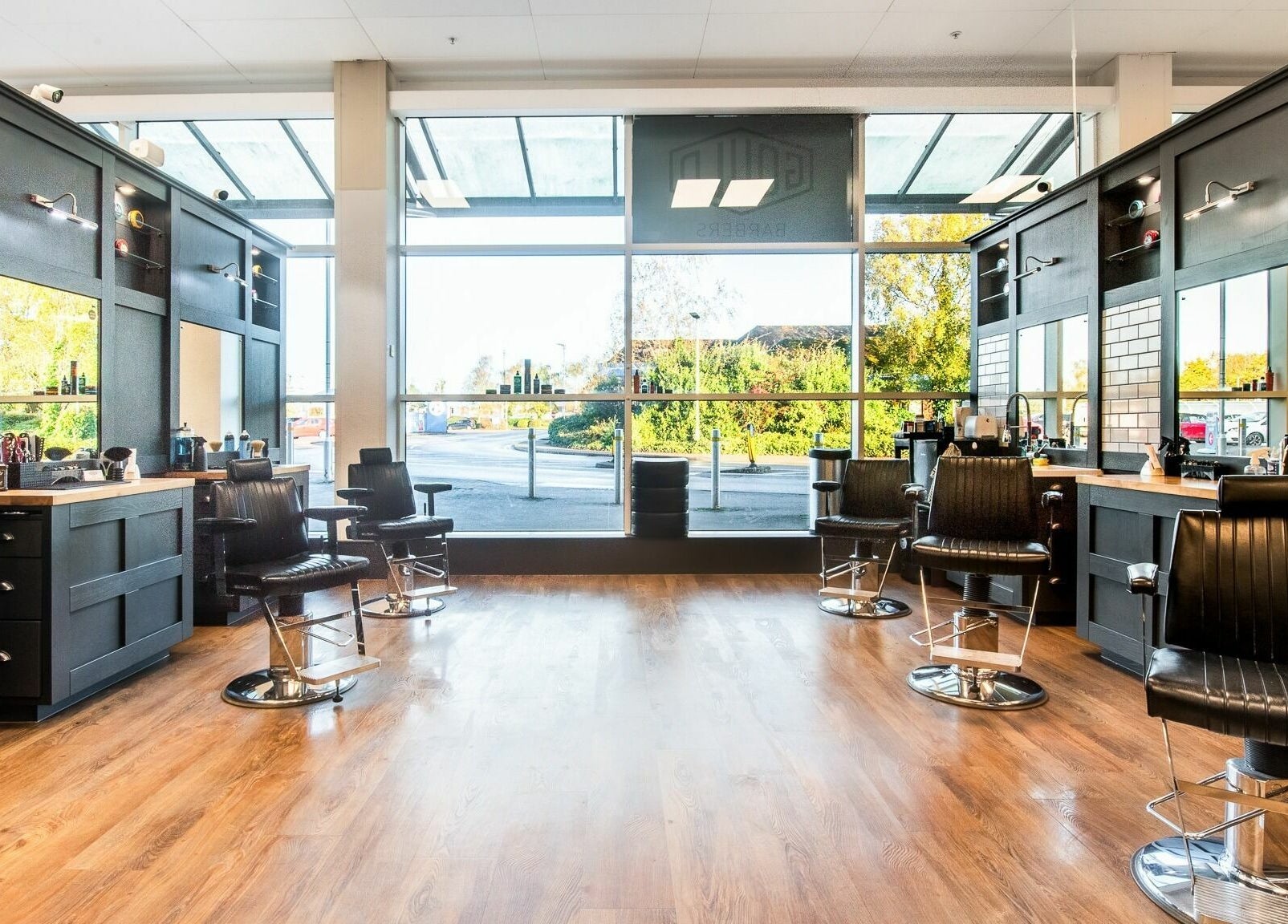 Bright, modern interior of Gould Barbers Newbury, Newbury, England, GB with sleek black chairs and large windows.