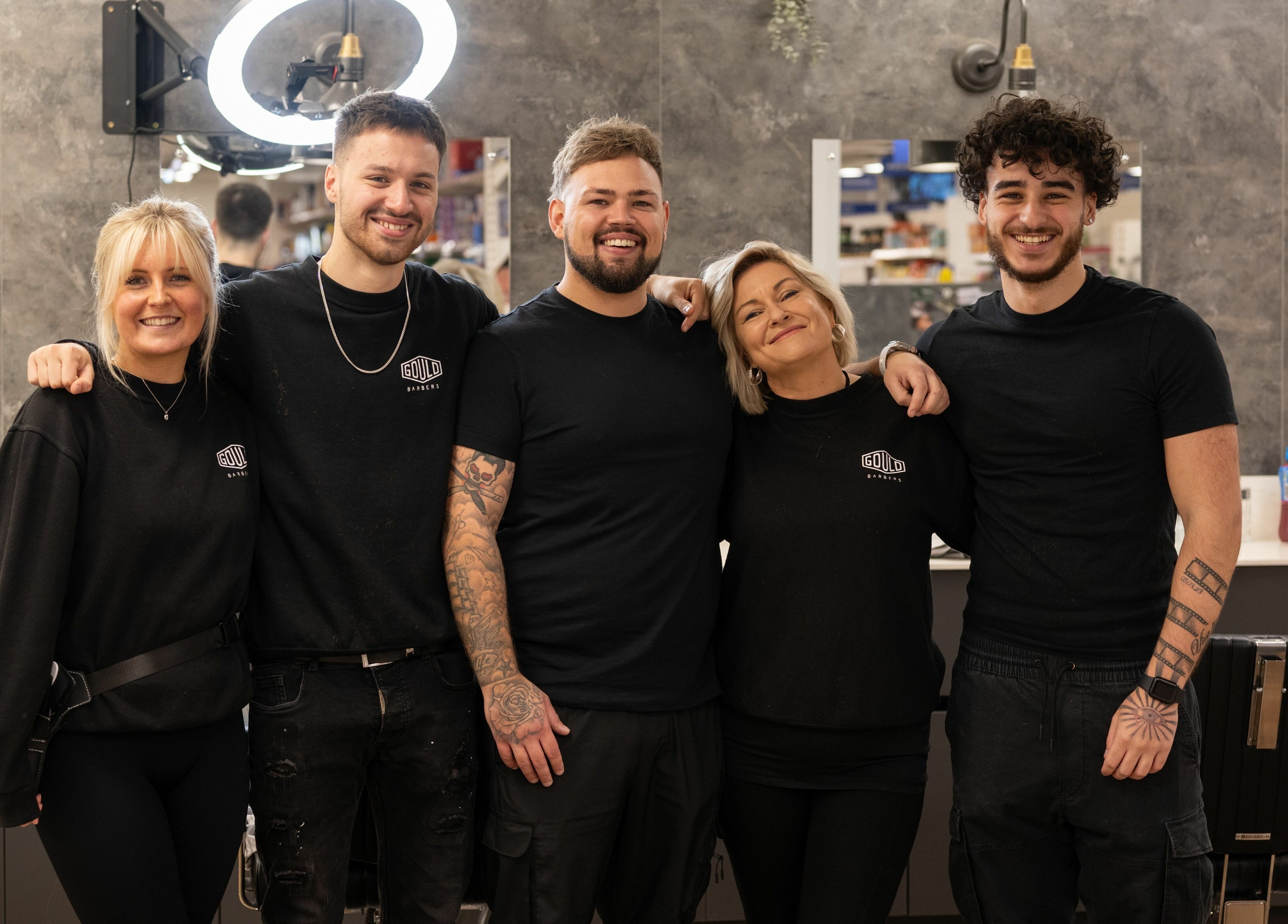 Friendly team at Gould Barbers Horsham in Horsham, England, GB, smiling inside the barbershop.