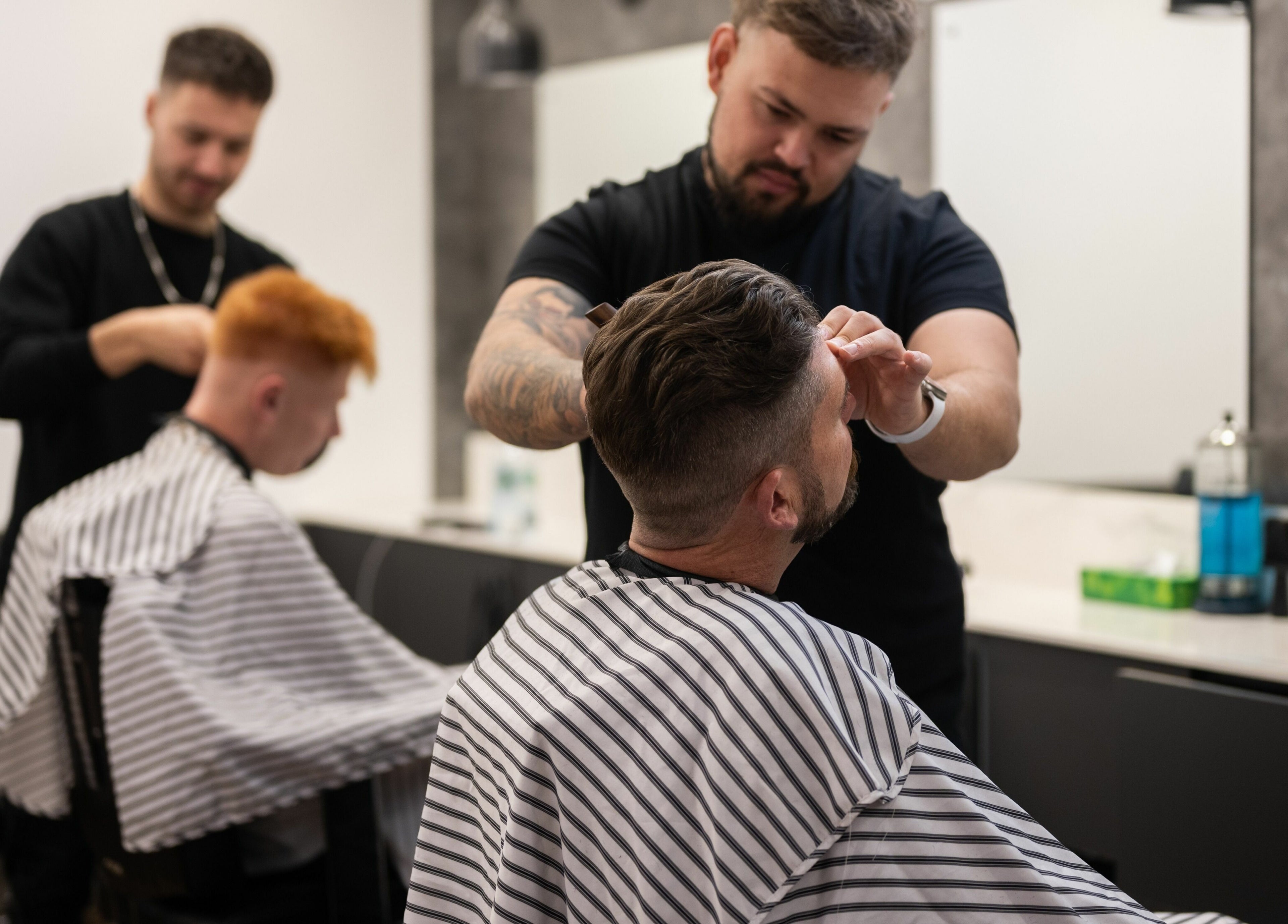 Barbers at Gould Barbers Horsham, Horsham, England, GB expertly cutting clients' hair in a modern salon.