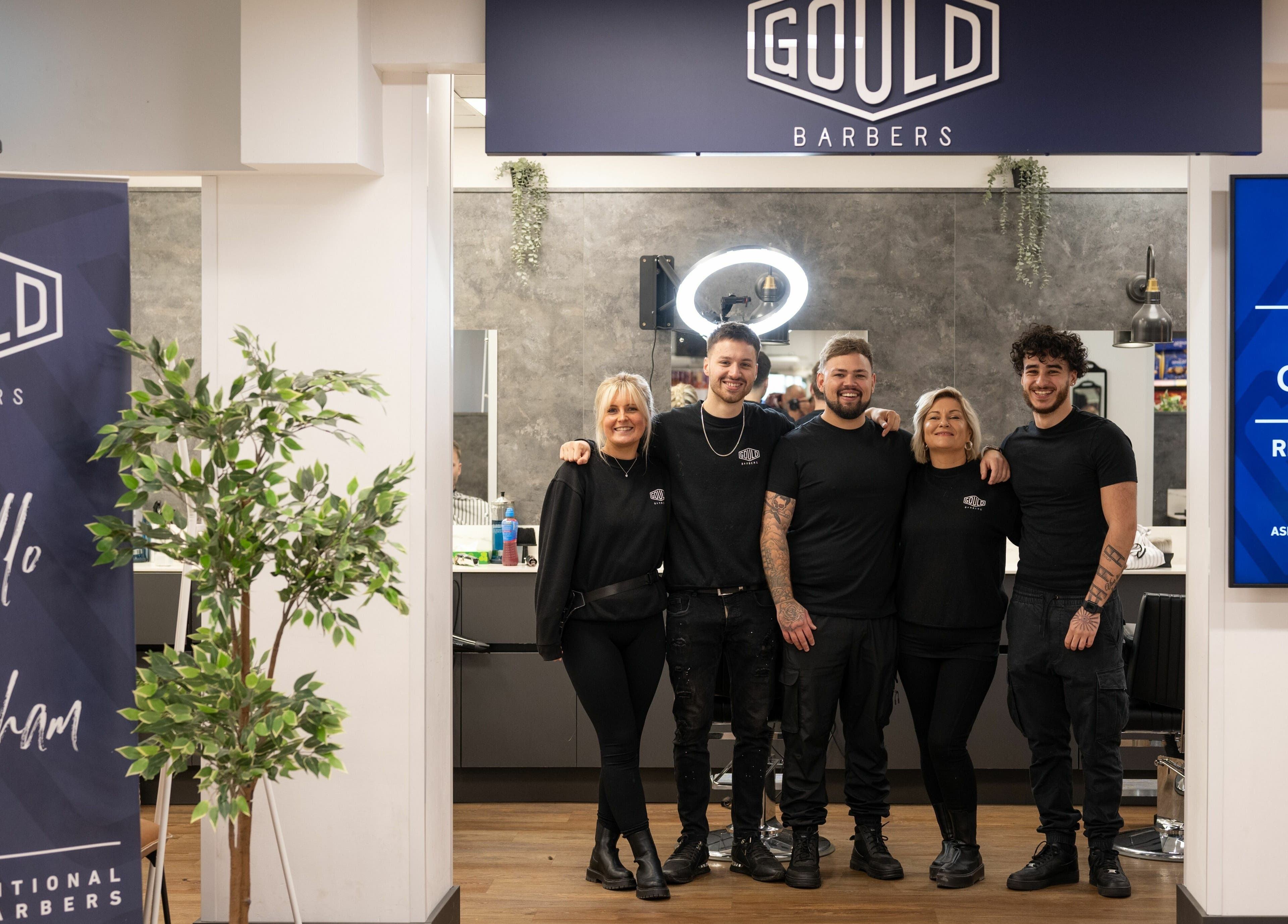 Team of hair stylists at Gould Barbers Horsham, Horsham, England, GB standing proudly at the salon entrance.