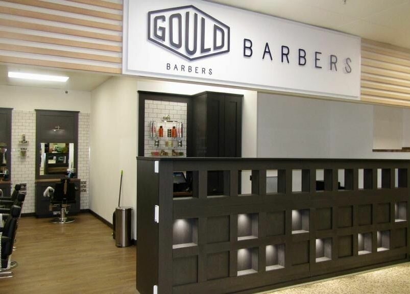 Stylish interior of Gould Barbers Hatfield, England, GB showing modern chairs and sleek decor.