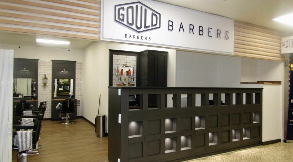 Stylish interior of Gould Barbers Hatfield, England, GB showing modern chairs and sleek decor.