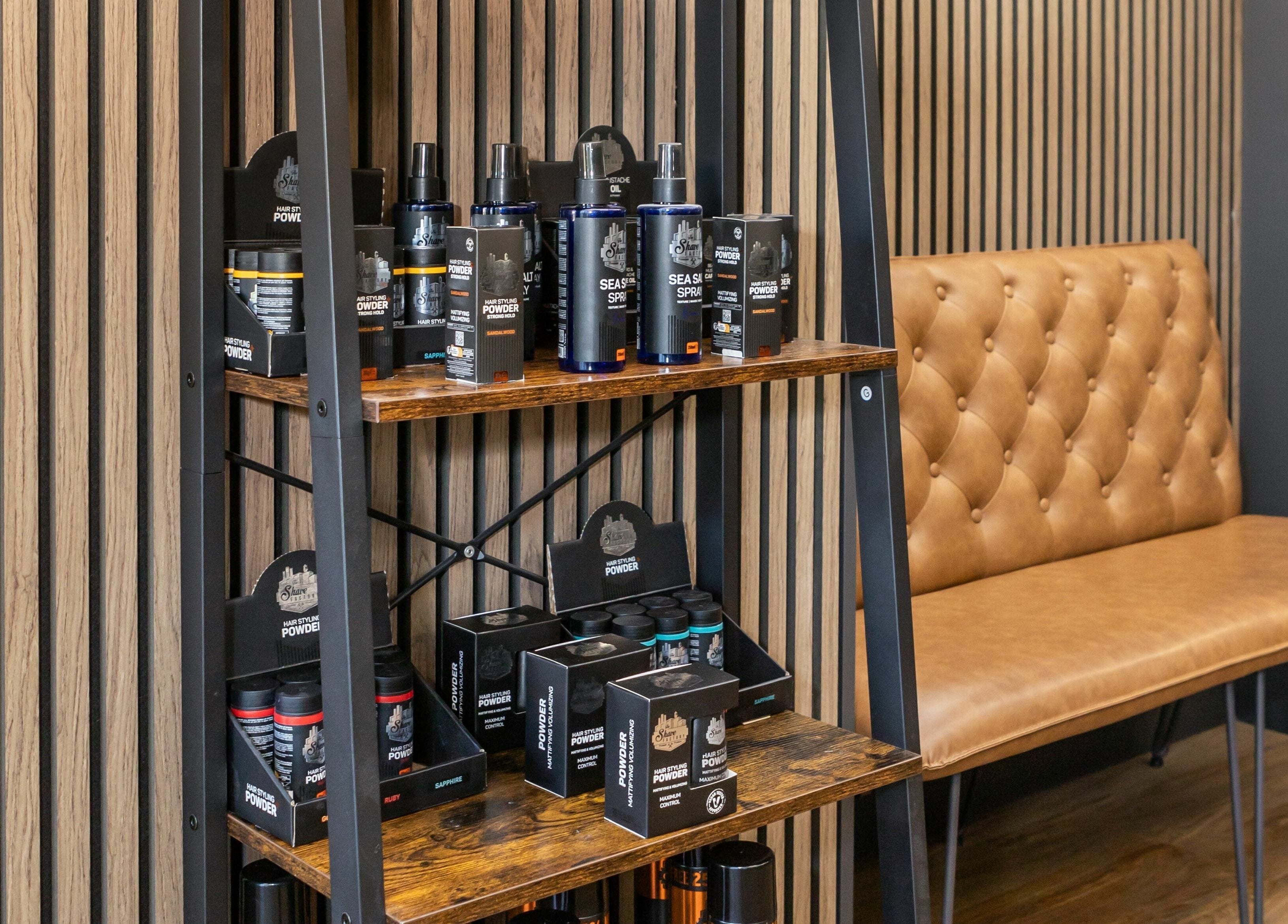 Product display at Gould Barbers Lakeside, Lakeside, England, GB with modern seating and wooden shelves.