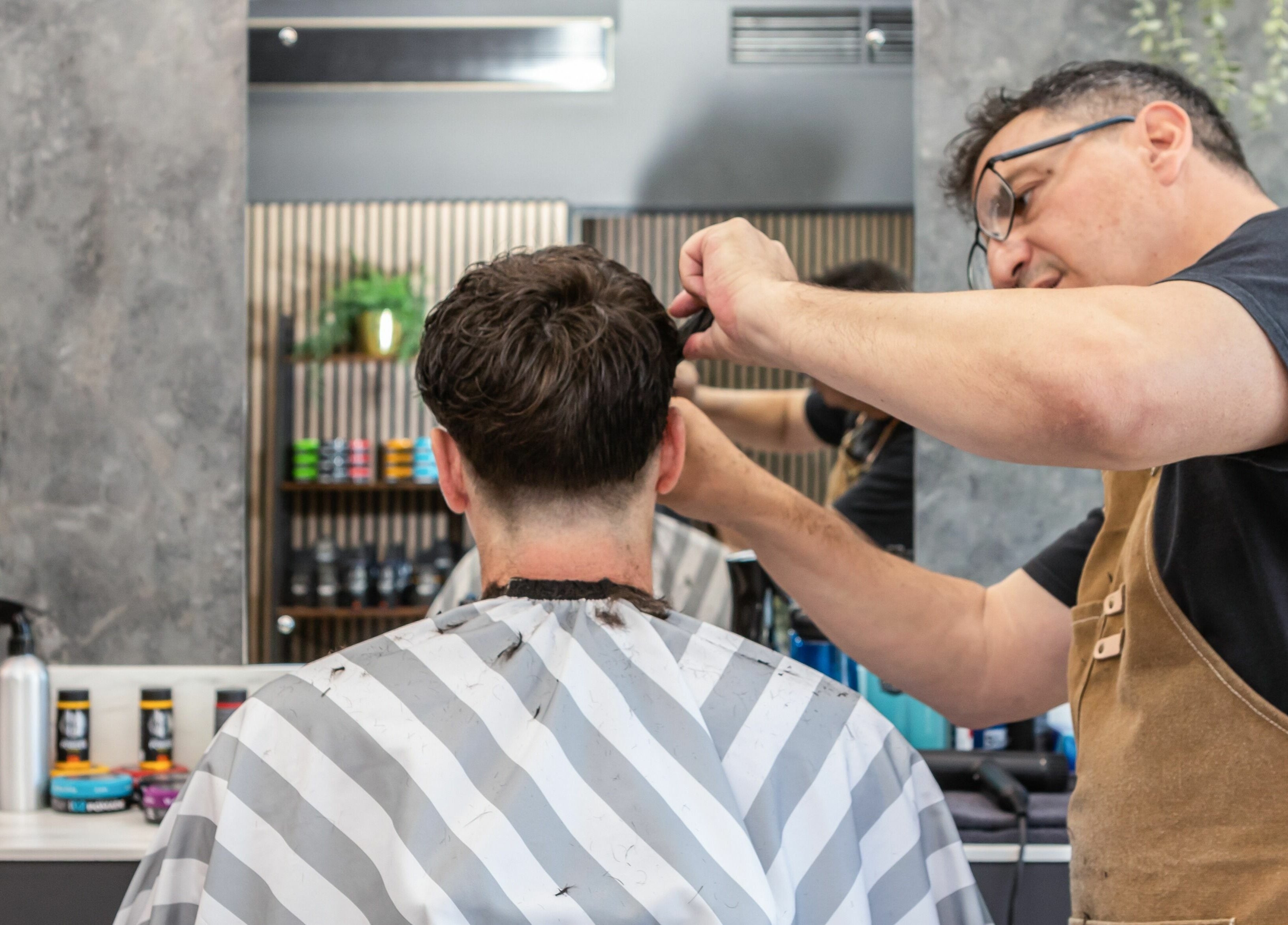 Skilled barber at Gould Barbers Lakeside in Lakeside, England, GB crafting a modern haircut with precision.