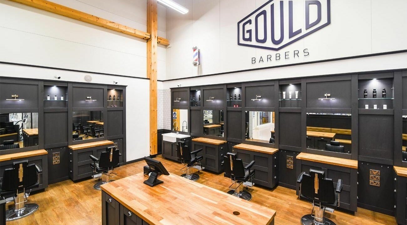 Elegant interior of Gould Barbers Newmarket, England, GB featuring modern styling stations and sleek decor.