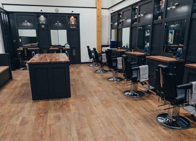 Stylish interior of Gould Barbers Stevenage in Stevenage, England, GB with sleek stations and wooden floors.