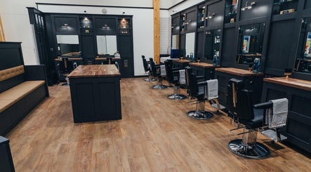 Stylish interior of Gould Barbers Stevenage in Stevenage, England, GB with sleek stations and wooden floors.