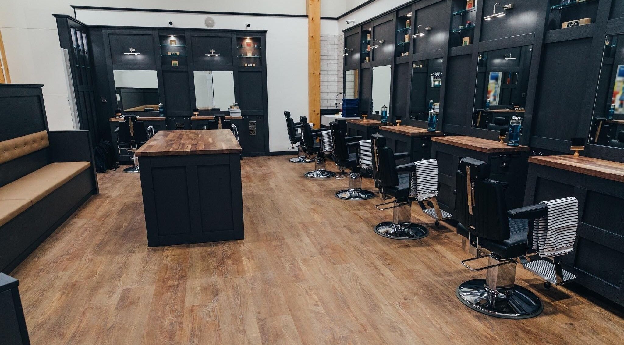 Stylish interior of Gould Barbers Stevenage in Stevenage, England, GB with sleek stations and wooden floors.