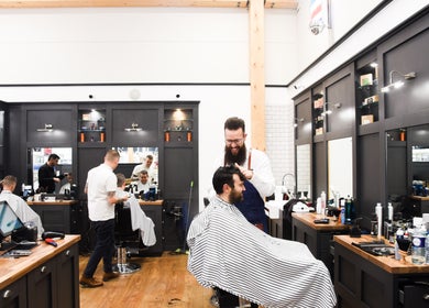 Modern barber shop interior at Gould Barbers Stevenage in Stevenage, England, GB with stylists at work.