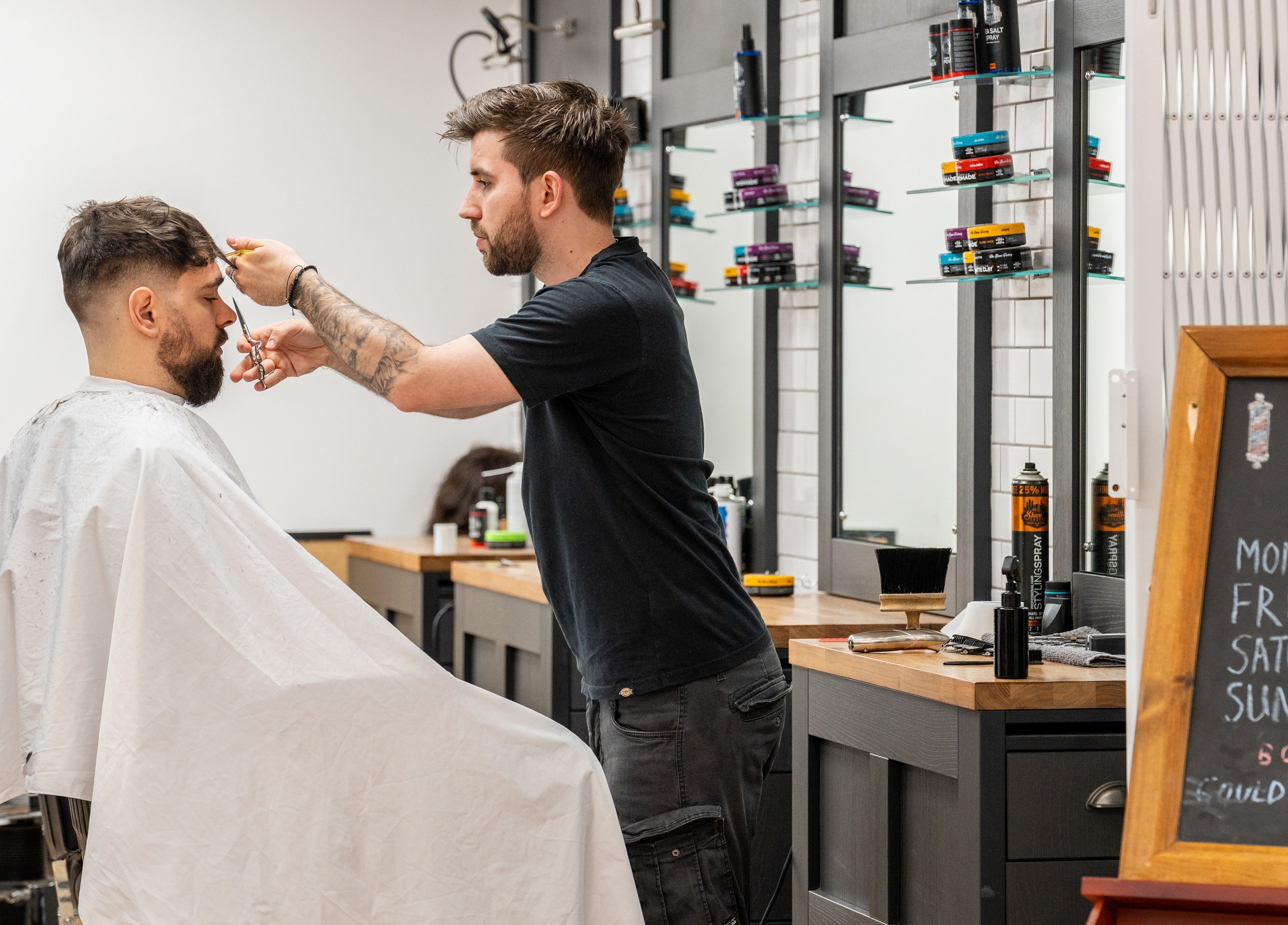 Barber at Gould Barbers Cheshunt in Cheshunt, England, GB giving a client a stylish haircut.
