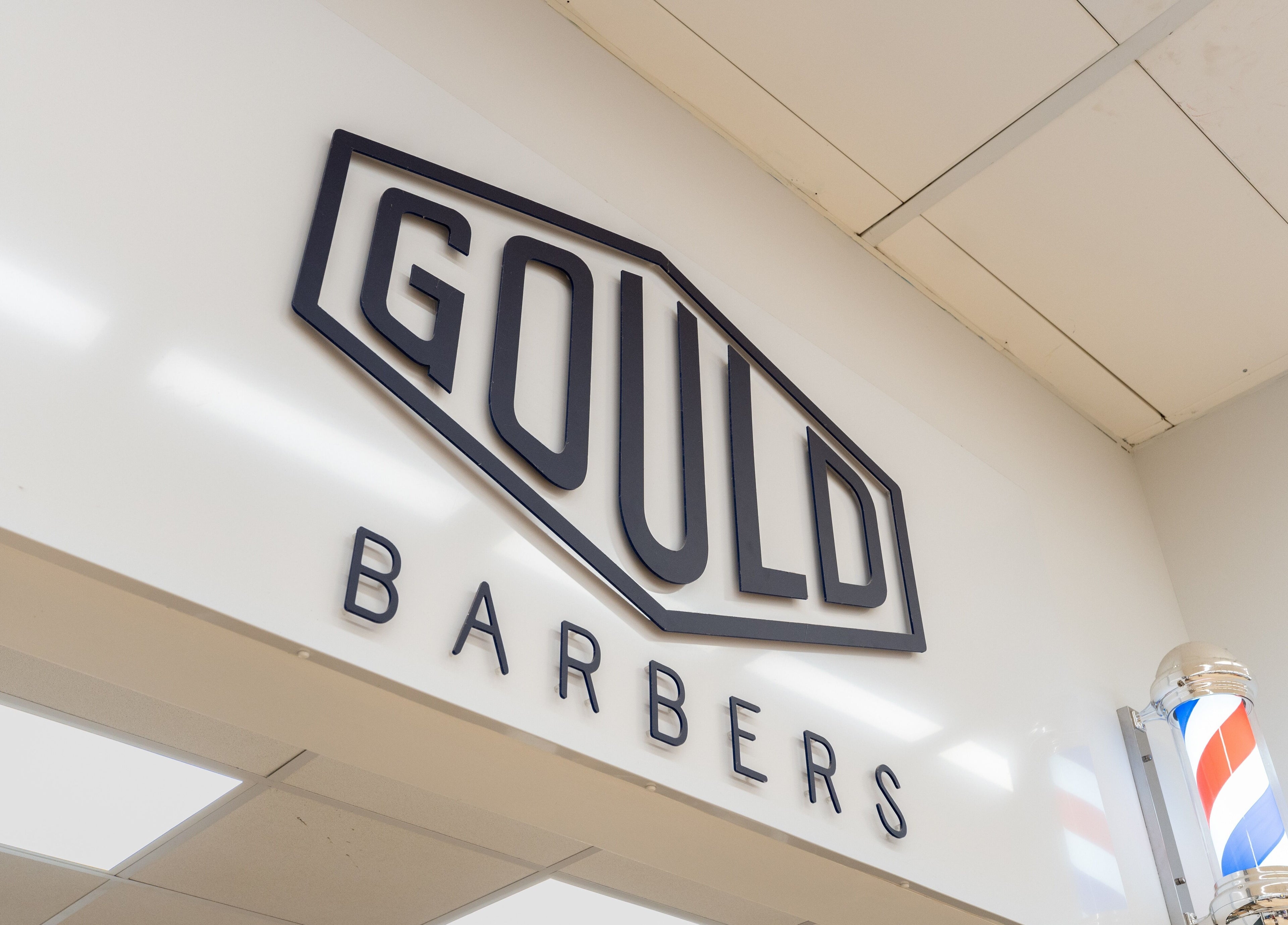 Entrance sign at Gould Barbers Cheshunt, located in Cheshunt, England, GB, featuring classic barber pole.