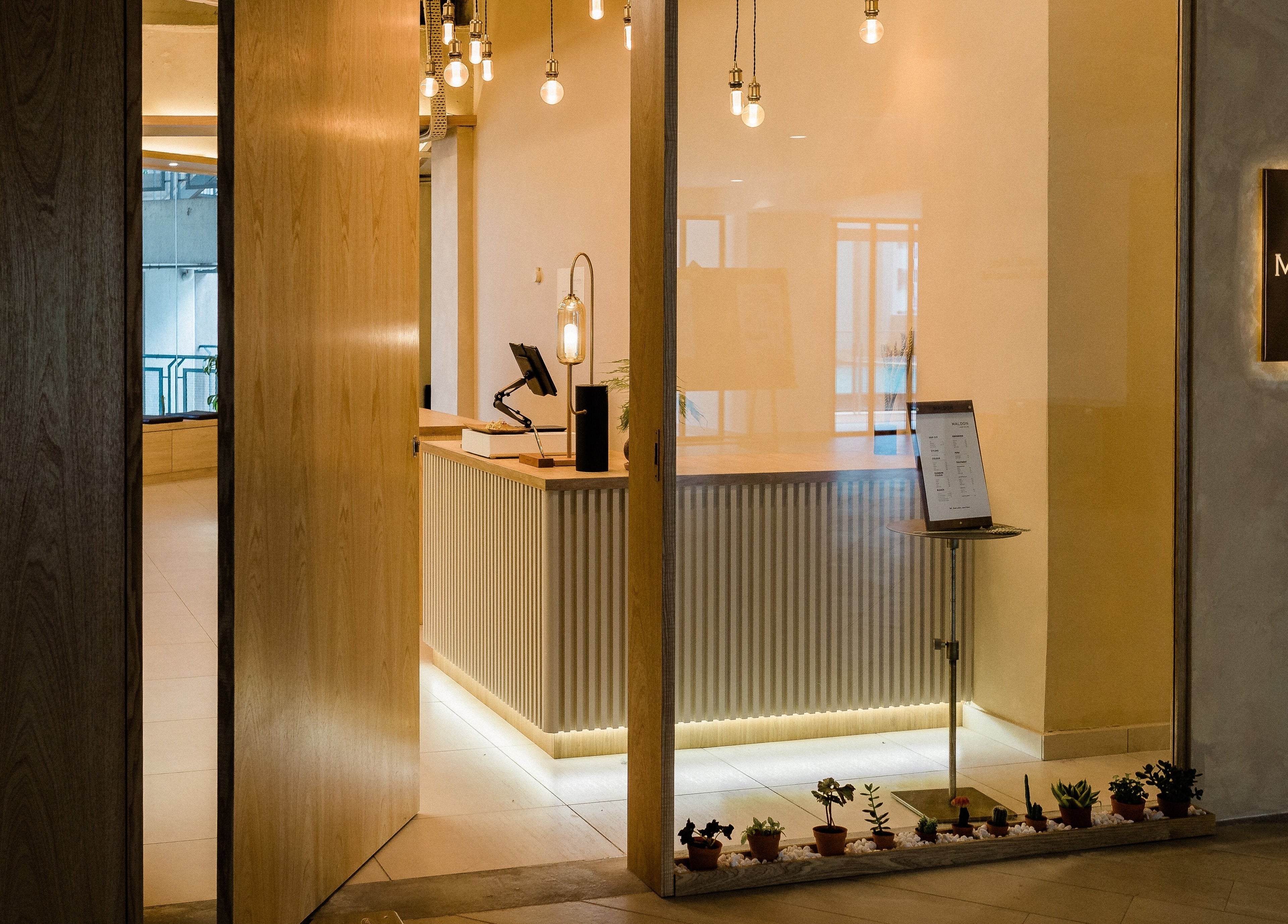 Elegant reception area of Maldon Salon, Kuala Lumpur, showcasing warm lighting and modern design.