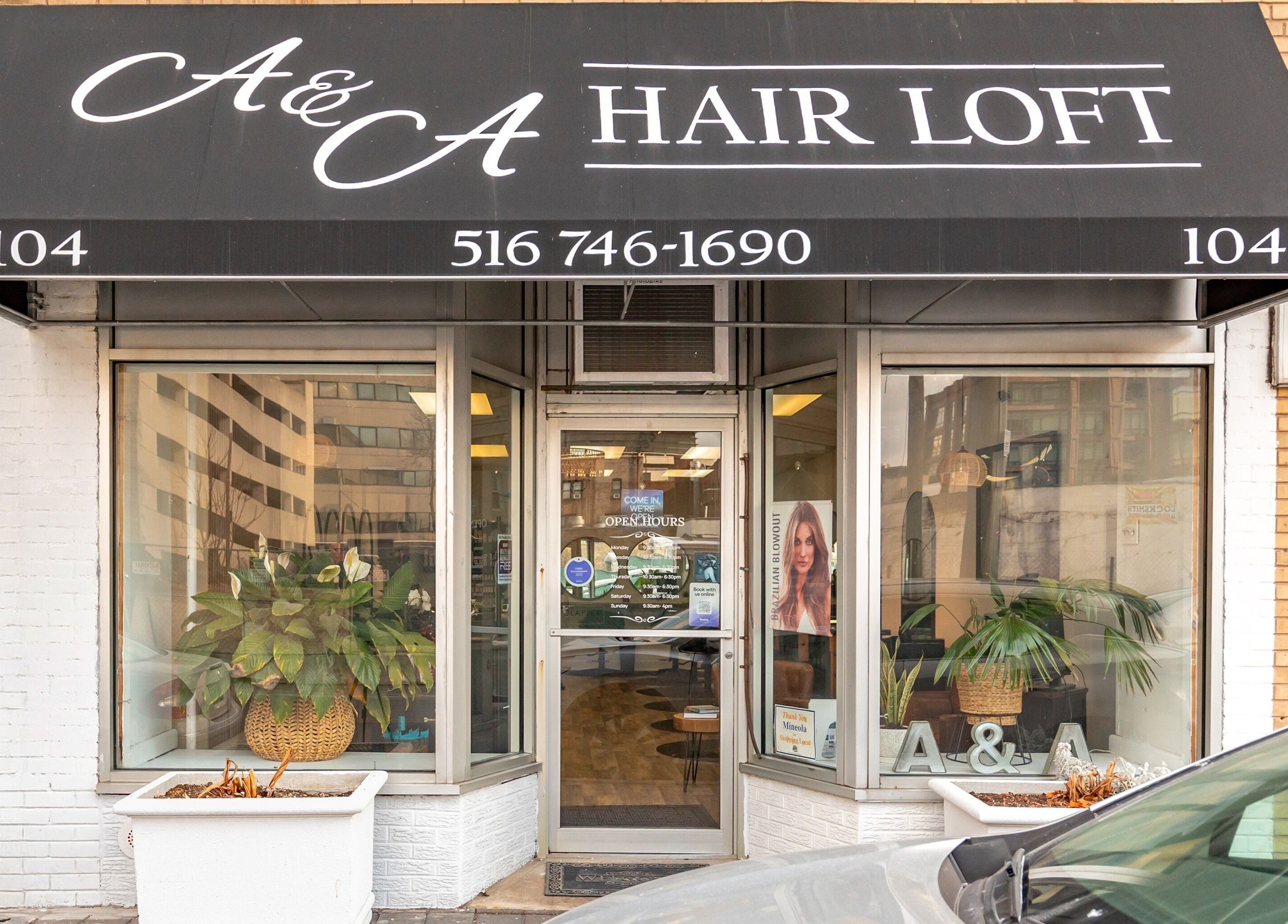 Front entrance of A&A Hairloft in Mineola, New York, showcasing stylish signage and greenery.