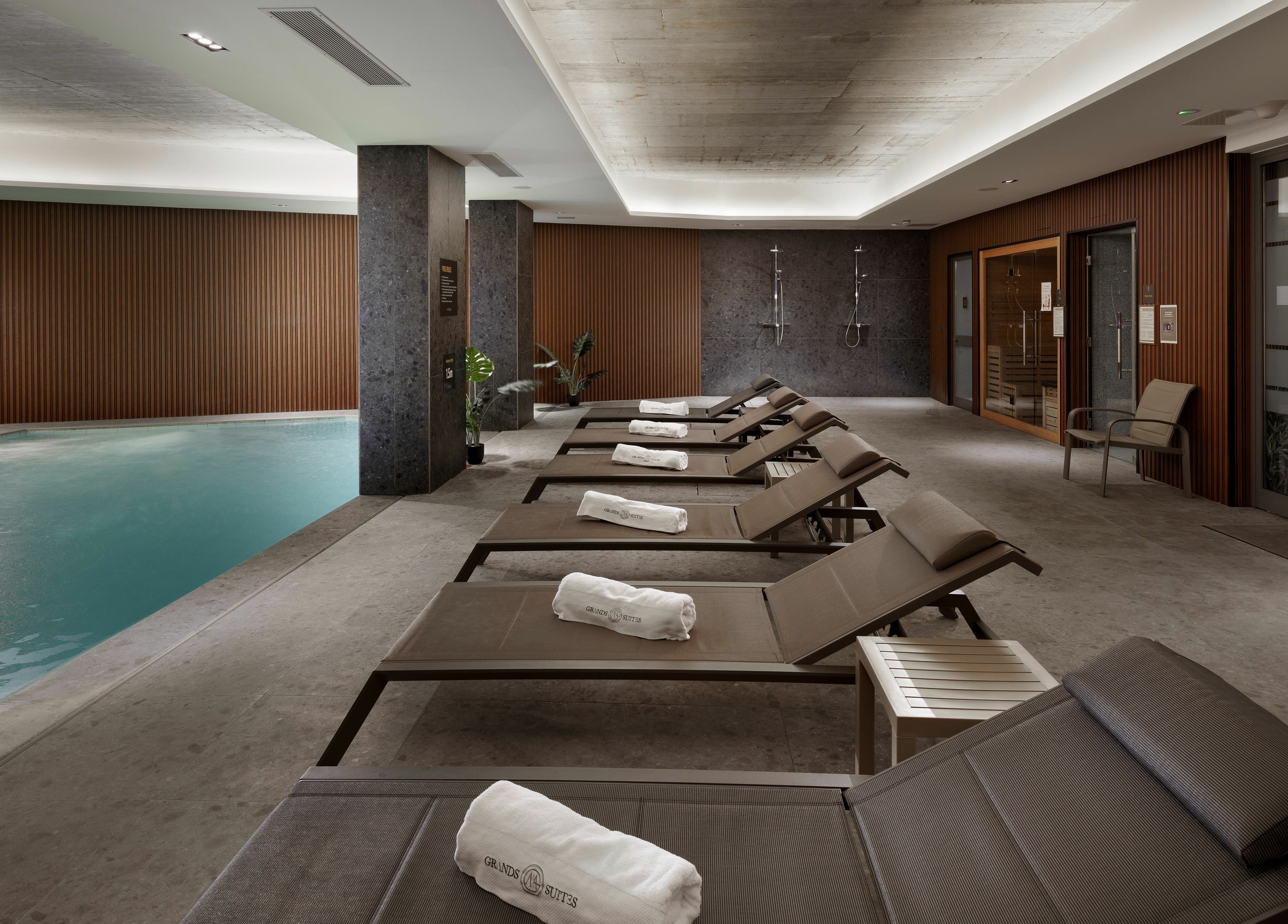 Relaxing poolside at Ease Spa, Gzira, MT with lounge chairs and soft lighting for a tranquil experience.