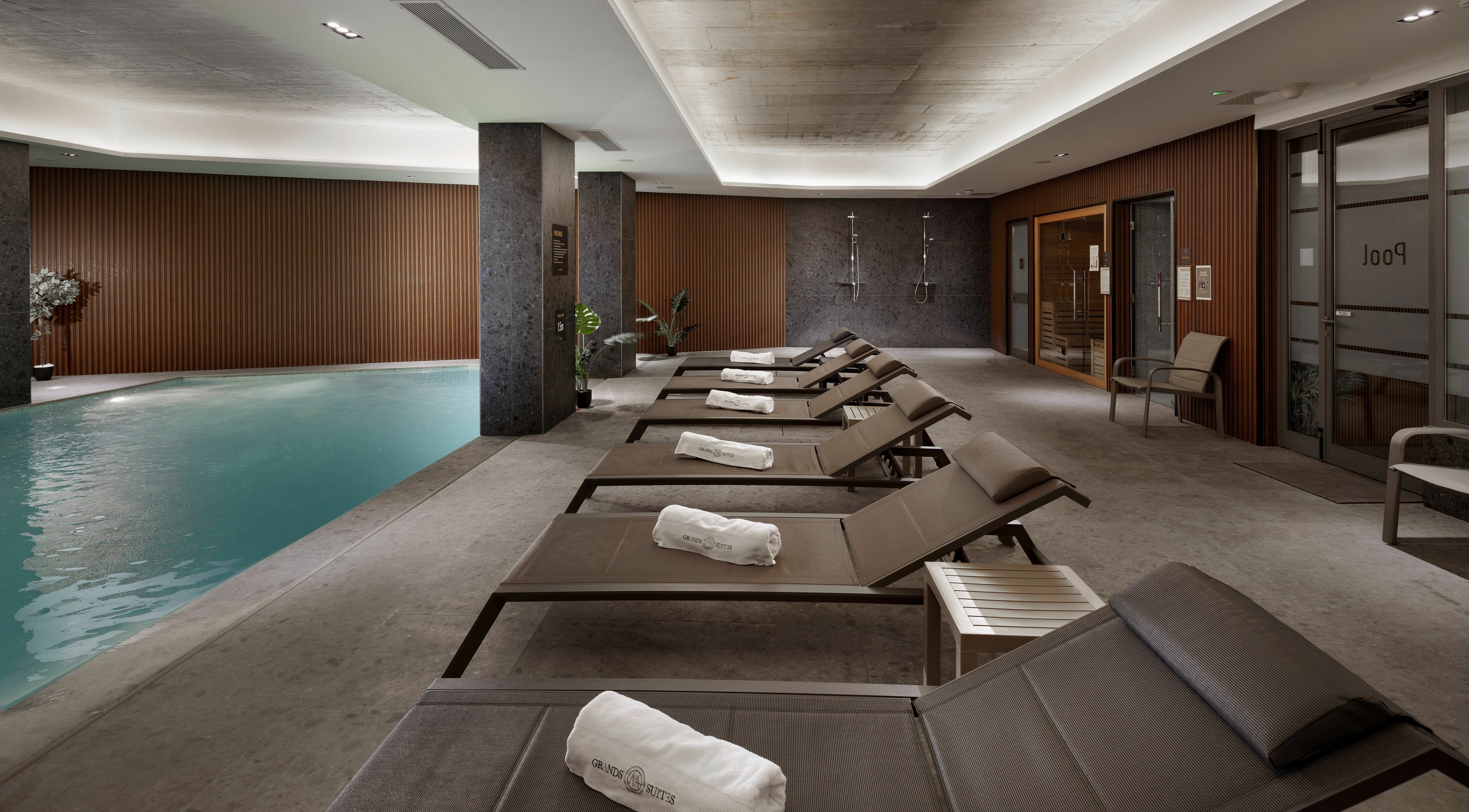 Relaxing poolside at Ease Spa, Gzira, MT with lounge chairs and soft lighting for a tranquil experience.