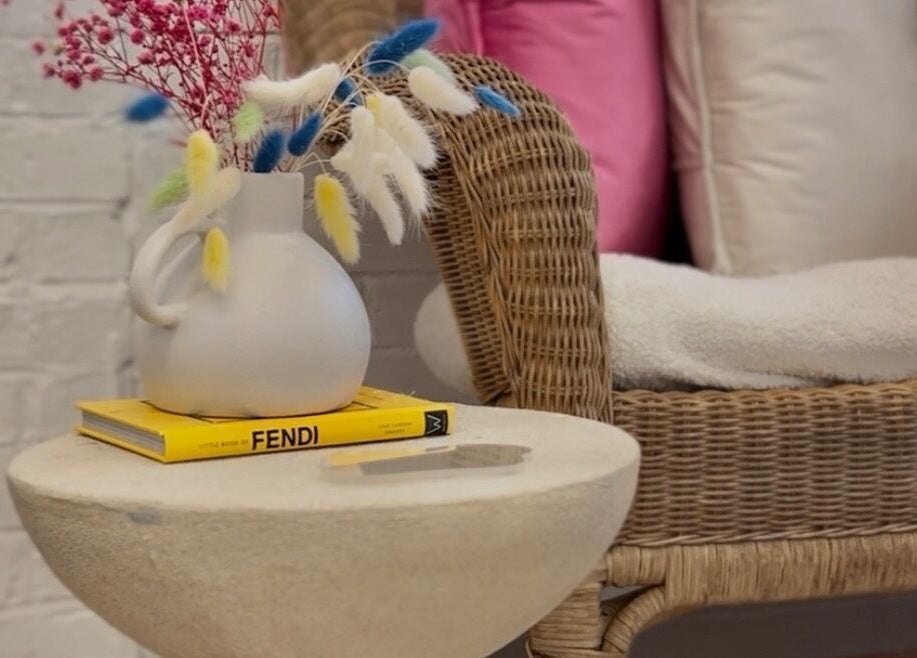 Elegant vase and book on table next to wicker chair at Saturate The Studio, Johnston, Wales, GB.