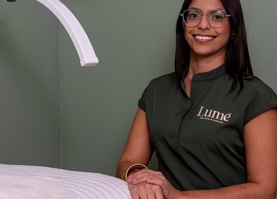 Profesional sonriente en LUMÊ, San Juan, PR, junto a una moderna lámpara de tratamiento.