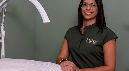 Profesional sonriente en LUMÊ, San Juan, PR, junto a una moderna lámpara de tratamiento.
