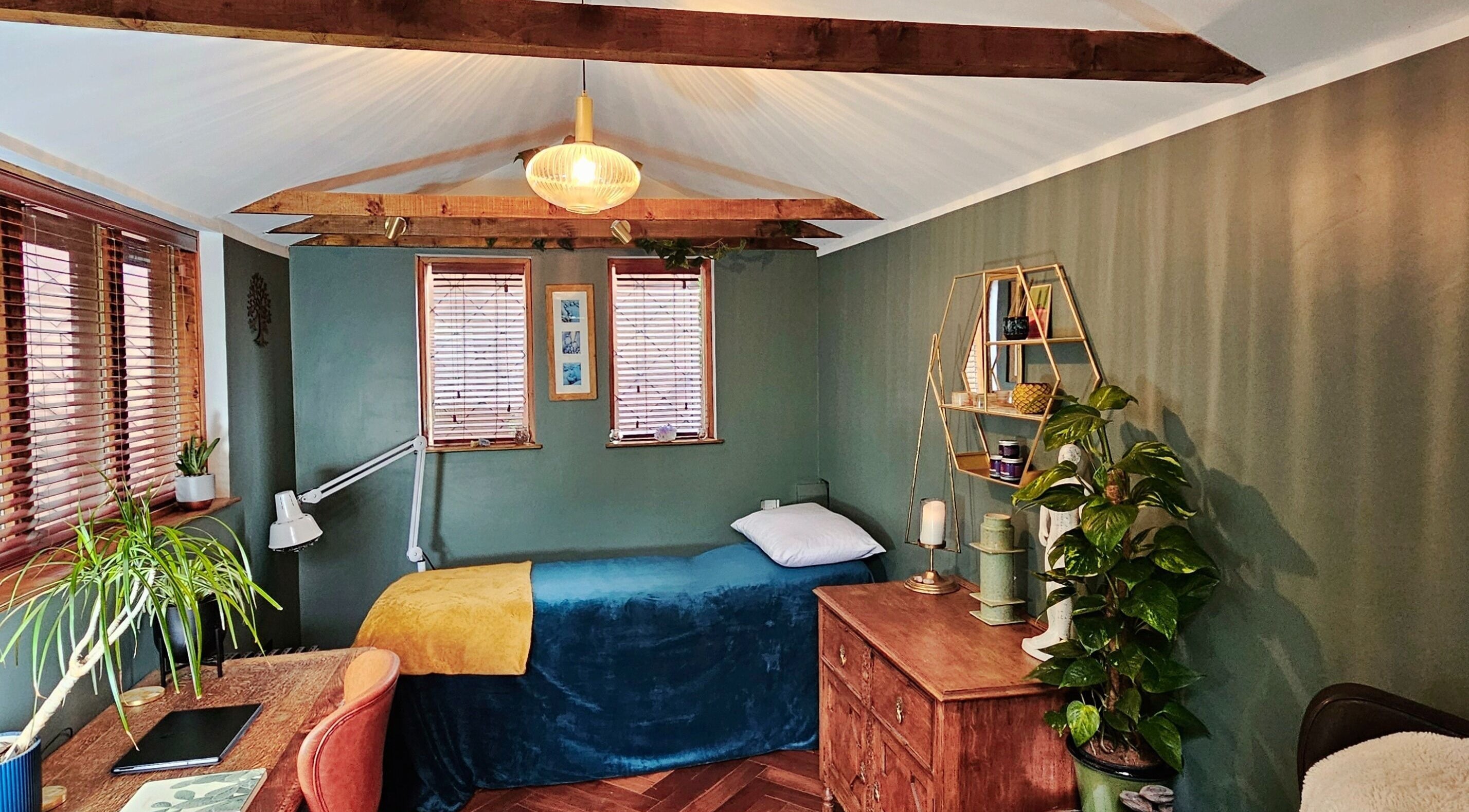Cozy treatment room at Exhale at The Garden Room, Didcot, England, GB, with a bed, plants, and wooden decor.