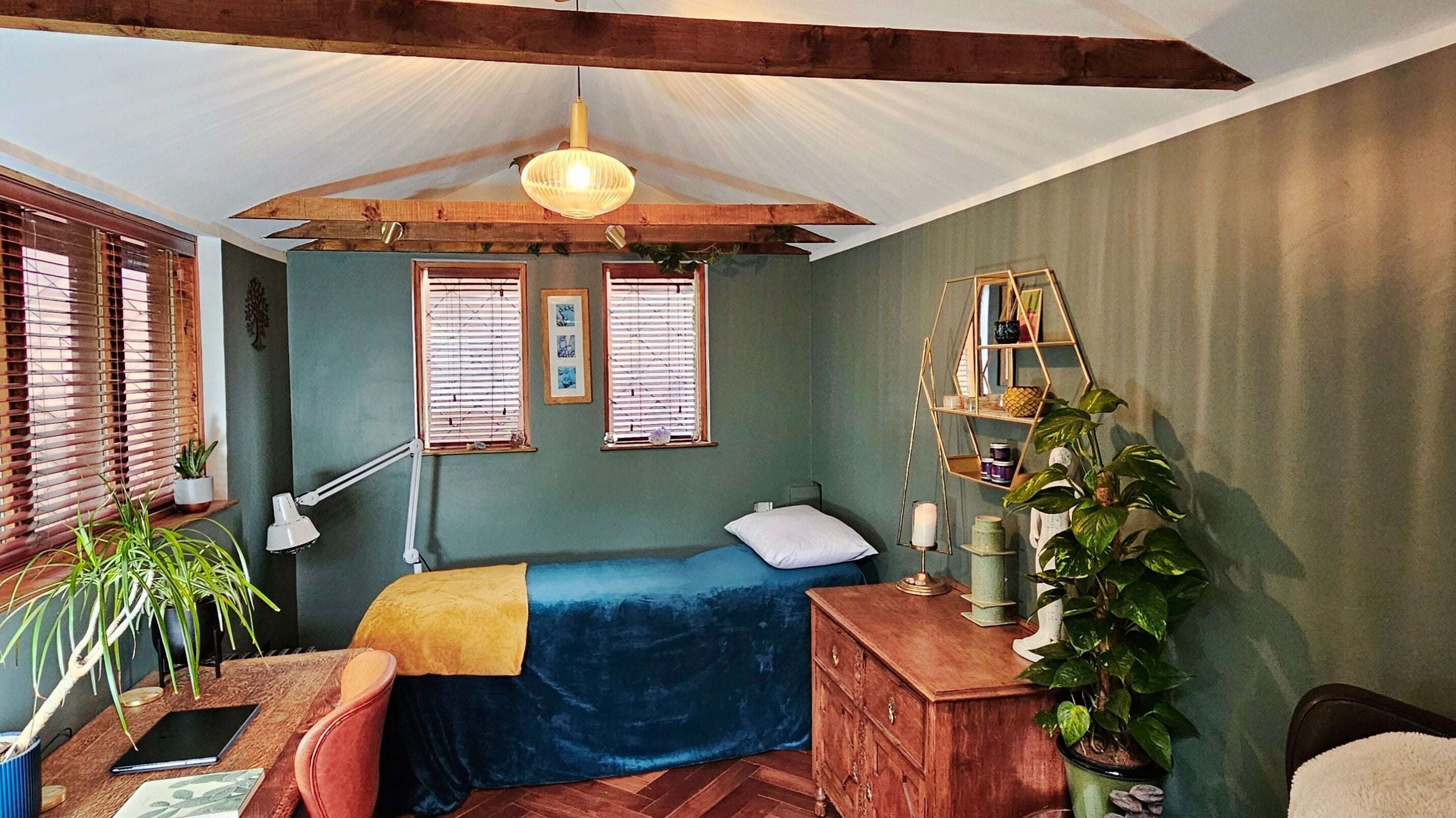 Cozy treatment room at Exhale at The Garden Room, Didcot, England, GB, with a bed, plants, and wooden decor.