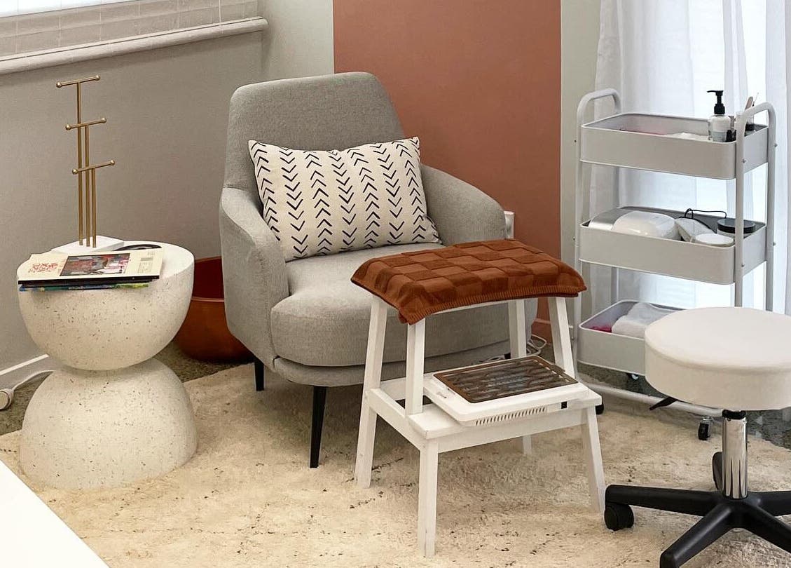 Comfortable seating area at Gloss Salon, Mangawhai, Northland, NZ, with a modern chair and accessories.