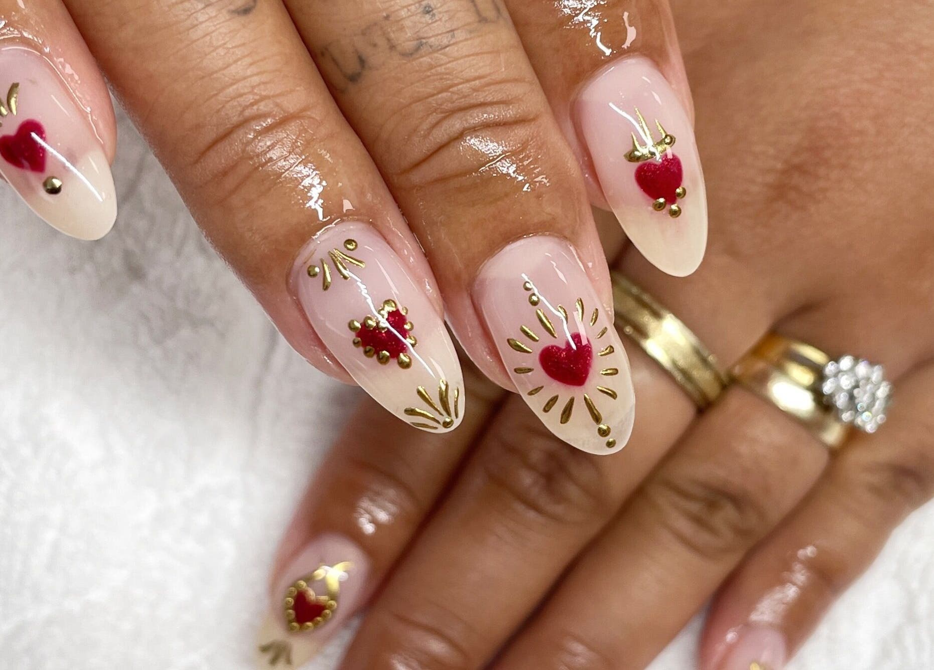 Stylish heart-themed nail art at Gloss Salon in Mangawhai, Northland, NZ, featuring gold accents on nude polish.