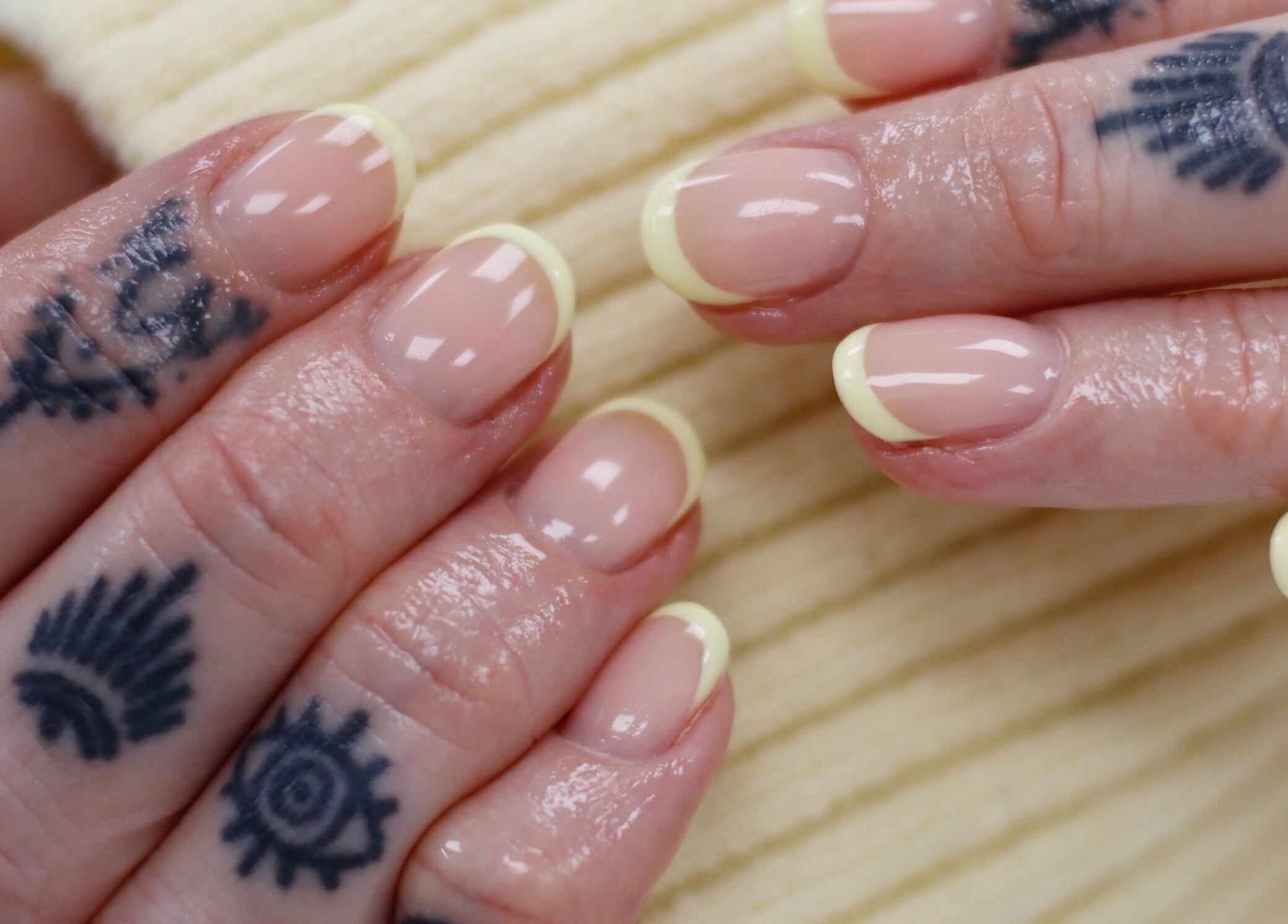 Stylish French manicure with tattoos at Gloss Salon, Mangawhai, Northland, NZ. Perfect for chic elegance.