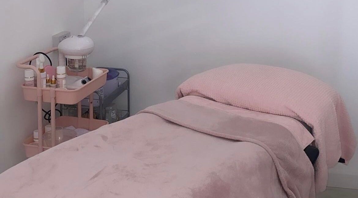 Relaxing treatment room at BeautybyB in Berkshire, England, GB with pink bedding and skincare products.