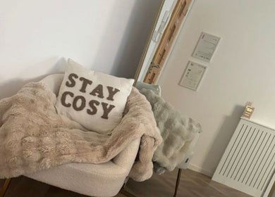 Comfortable chair with a 'stay cosy' pillow at Glow Skin Bar, Newcastle, England, GB.