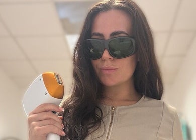 Professional laser hair removal at Glow Skin Bar, Newcastle, England, GB. Woman holding laser equipment.