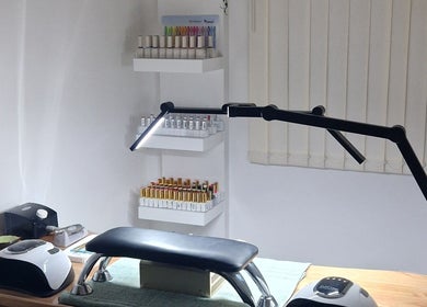 Modern nail station at Ria Dharni, Crawley, England, GB, featuring organized shelves with nail polish colors.