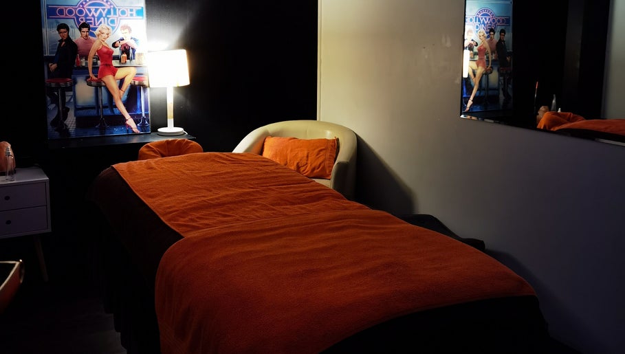 Cozy massage room at Empire Day Spa, Richmond, Victoria, AU, featuring dim lighting and red decor.
