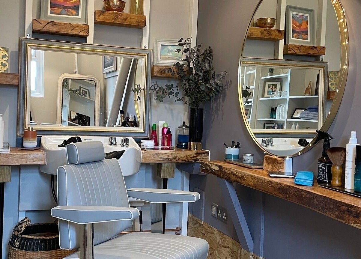 A stylish salon setup at The Curl Studio in Cullompton, England, GB, featuring mirrors and grooming products.