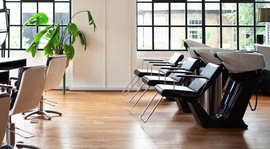 Modern salon interior at Hannah Domney - Hackney, London, England, GB, featuring sleek black wash stations.