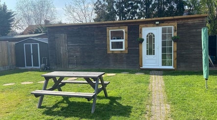 Peaceful garden at LavenderBlue HQ, Herne Bay, England with wooden building and picnic table.