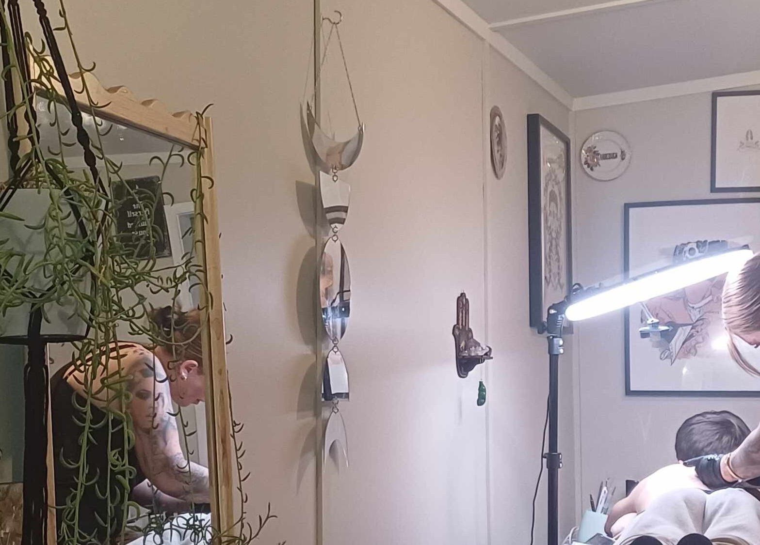 Stylish tattoo session at Made&Marked by AmyLouise, Whangarei, Northland, NZ with decorative mirrors and plants.