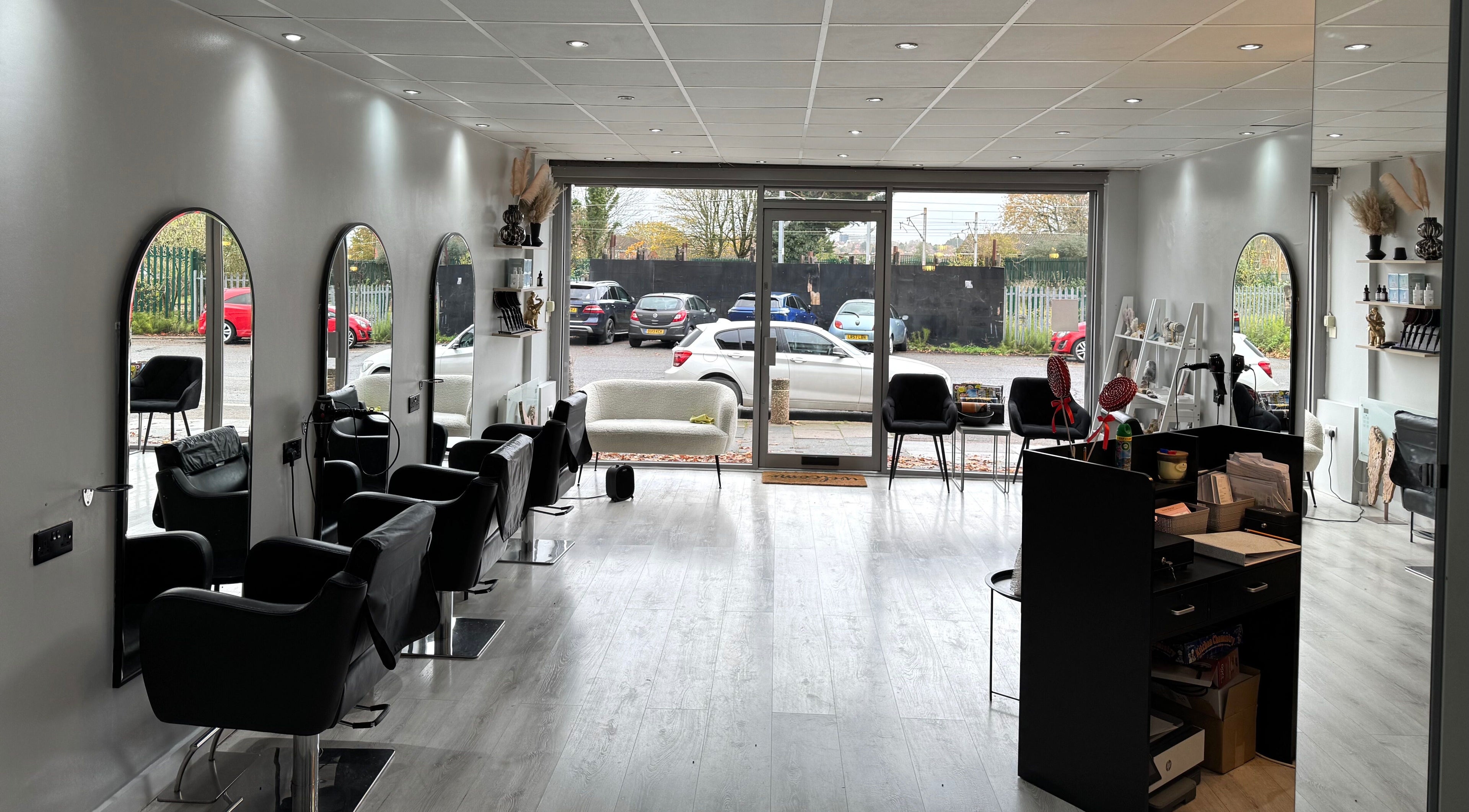 Chic and modern salon interior at By Olivia Hines in Barnet, England, GB with stylish black chairs and mirrors.