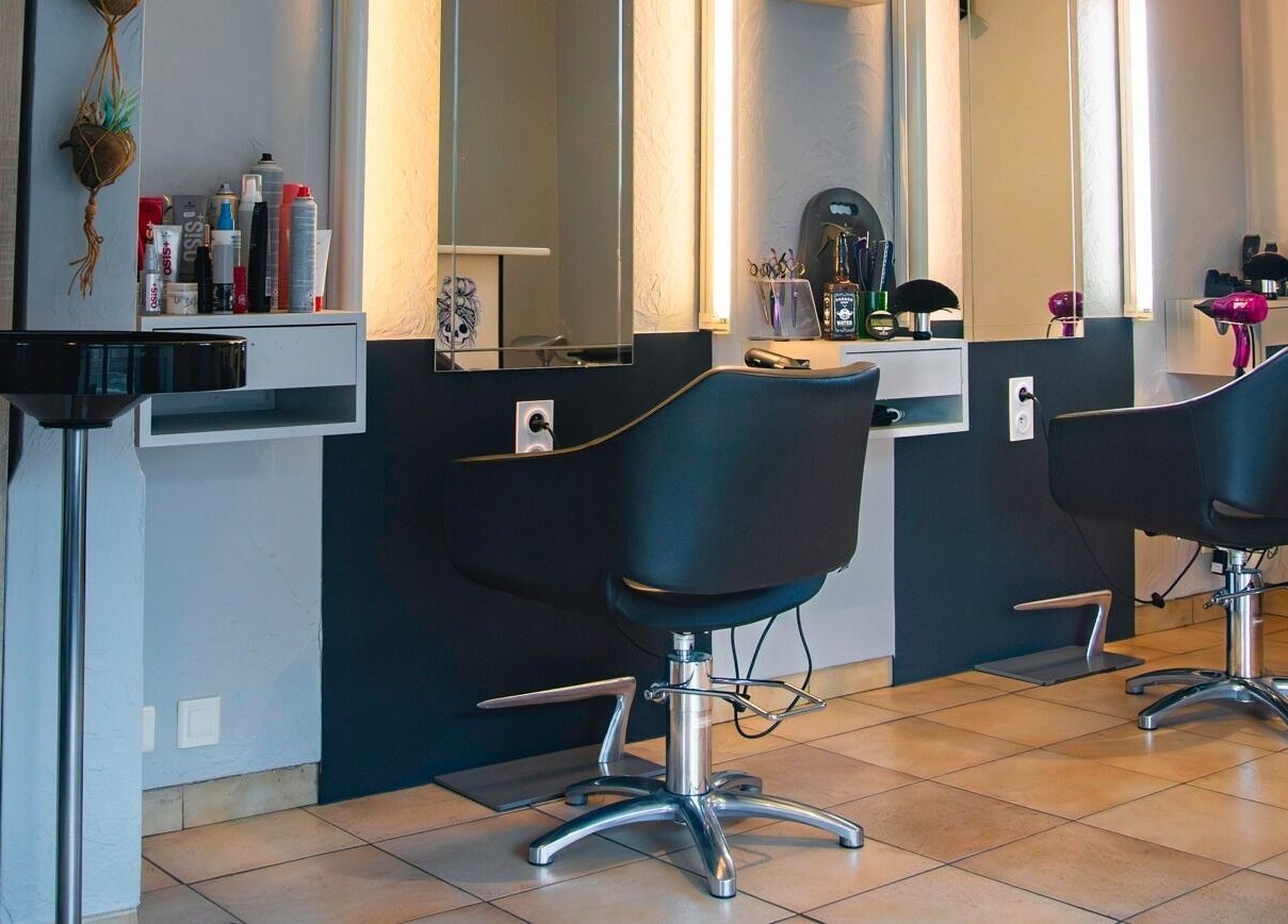 Intérieur moderne de salon chez Imagin'hair à Bains, Auvergne-rhône-alpes, FR, avec fauteuils élégants et éclairage doux.