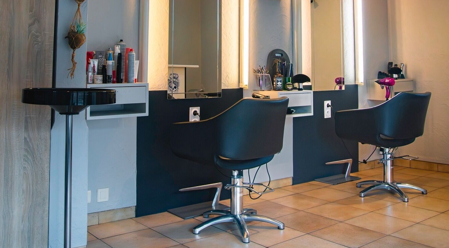 Intérieur moderne de salon chez Imagin'hair à Bains, Auvergne-rhône-alpes, FR, avec fauteuils élégants et éclairage doux.