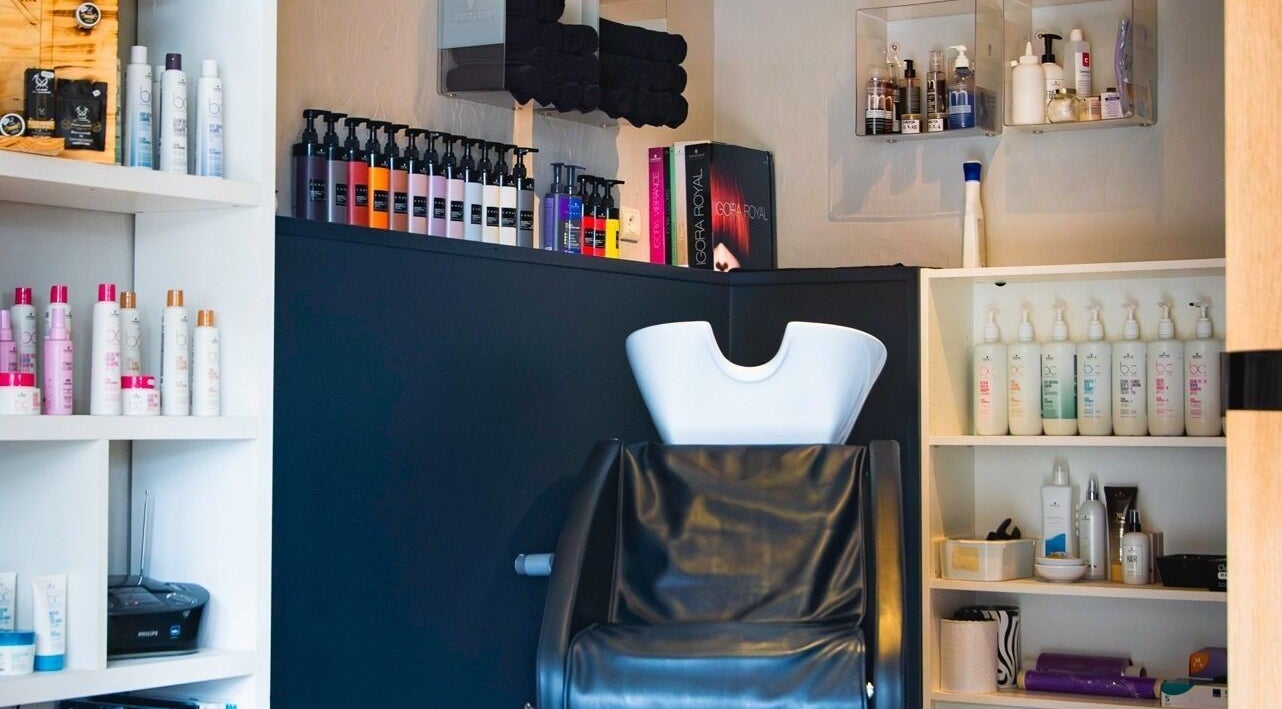 Espace de soins chic chez Imagin'hair, Bains, Auvergne-rhône-alpes, FR avec produits et fauteuil moderne.