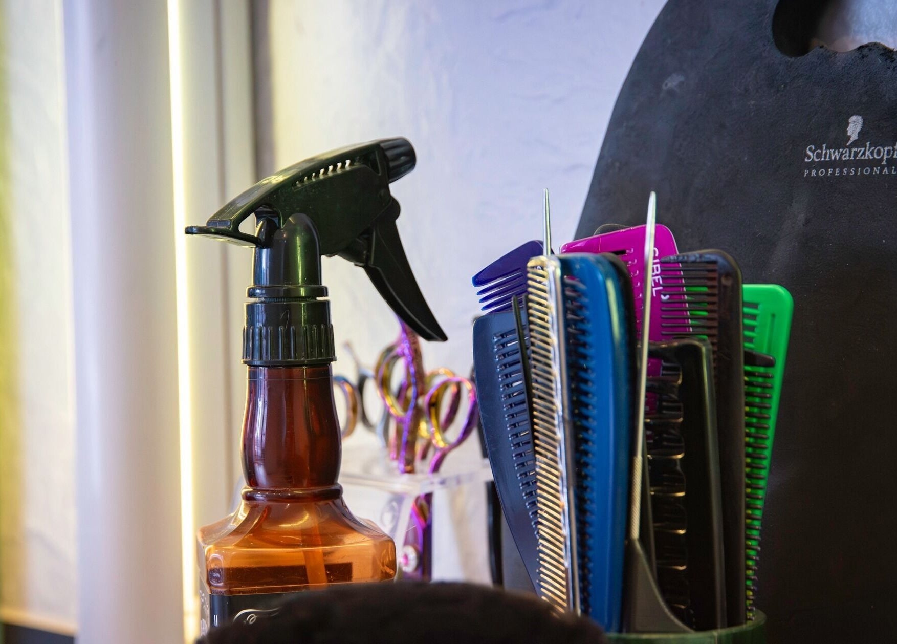 Outils coiffure à Imagin'hair, Bains, Auvergne-rhône-alpes, FR. Peignes colorés et vaporisateur en vitrine.