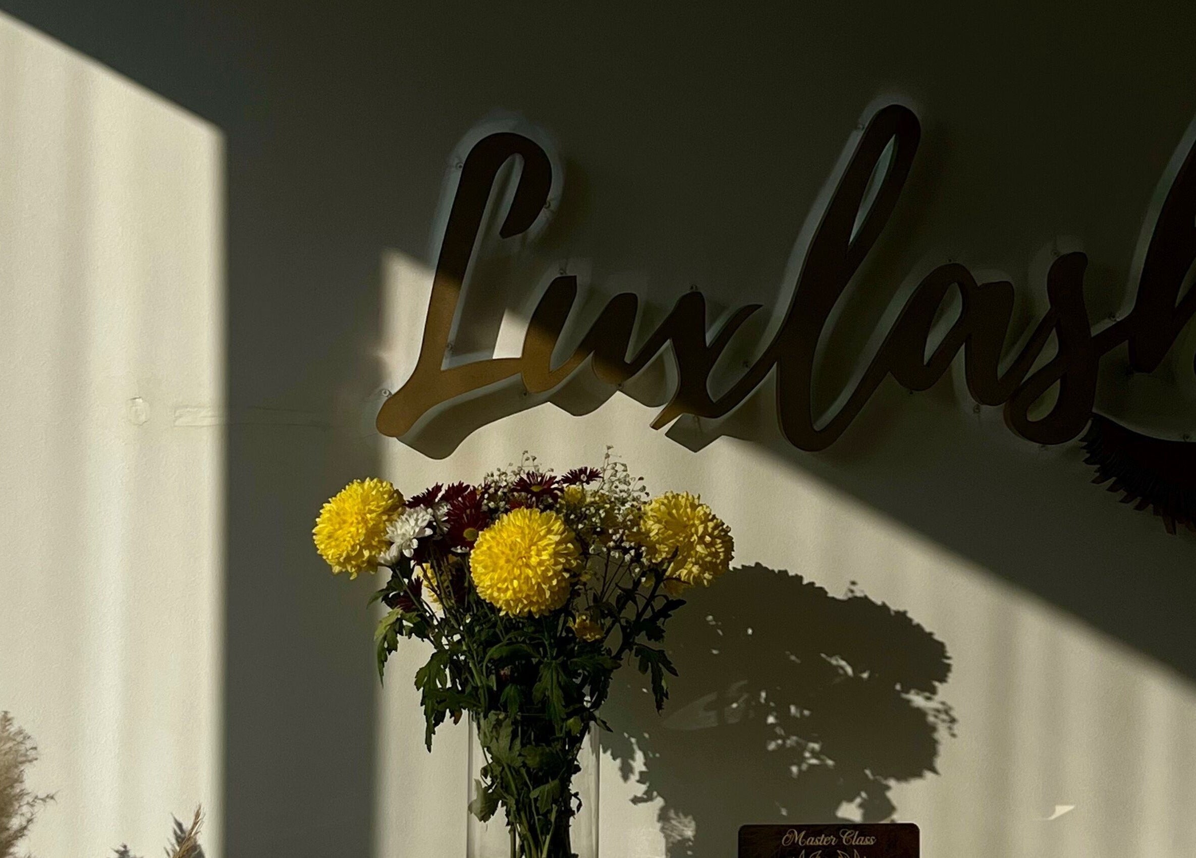 Διακόσμηση με λουλούδια στο Luxlashes by Mariana, Πειραιάς, GR, επάνω από το λογότυπο του καταστήματος.