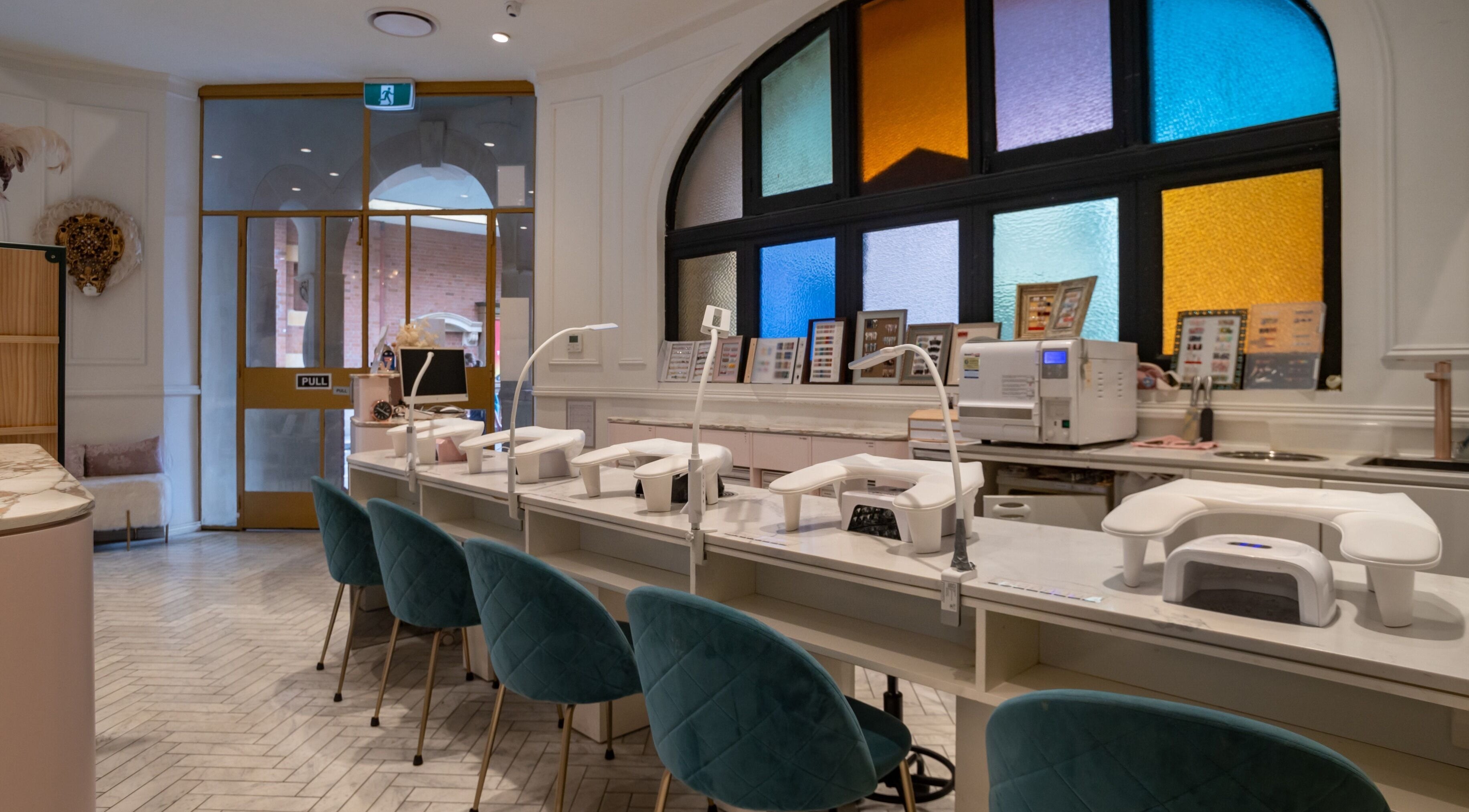 Interior view of Tiara Nail Spa in Haymarket, New South Wales, AU showcasing sleek nail stations and colorful windows.