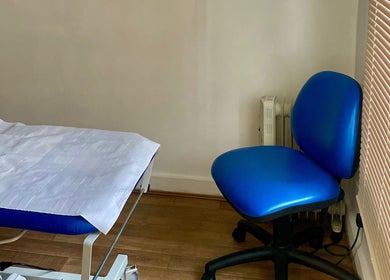Calm treatment room at Intuitive Bodywork, Rickmansworth, England, GB, featuring a massage bed and blue chair.