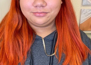 Model with bright red hair at Foxy Gyal Beauty, Las Vegas, Nevada, US, highlighting their vibrant hair services.